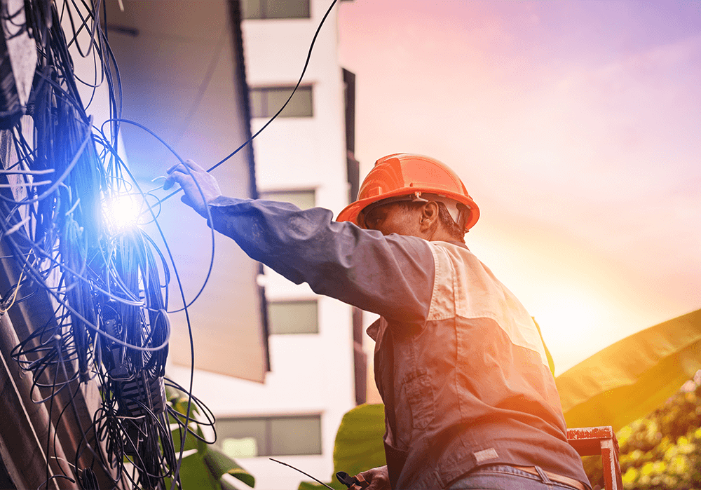 Electrician working on wires from a building